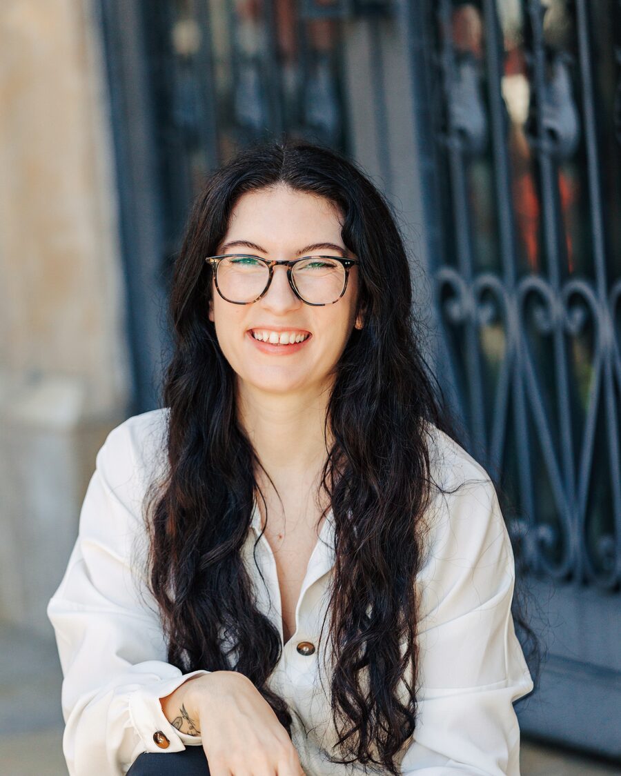 McKenna Pasquale, founder of Sagewave Web Design, smiling in front of an iron gate